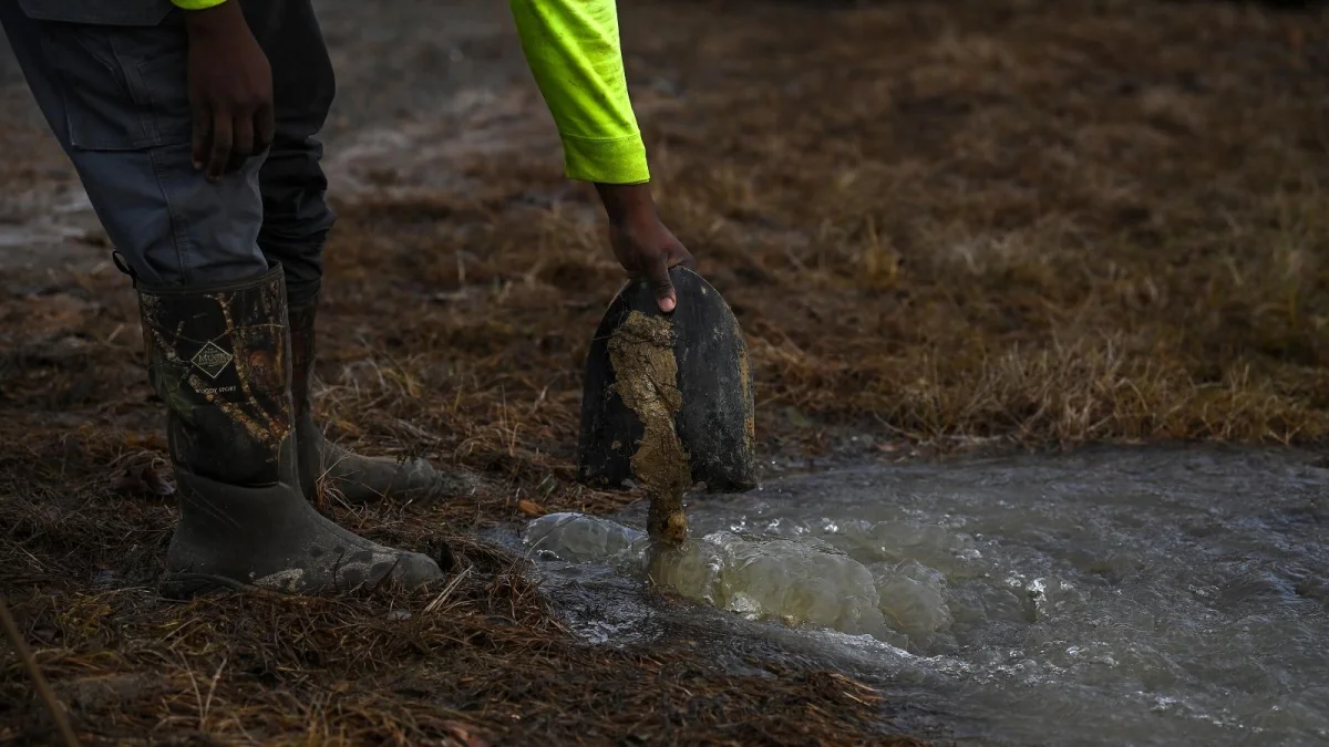 A person holds a shovel in standing water